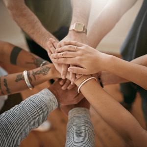 Grupo de personas uniendo sus manos simbolizando la accesibilidad del PFBEC® para centros de formación, profesionales, estudiantes y empresas.