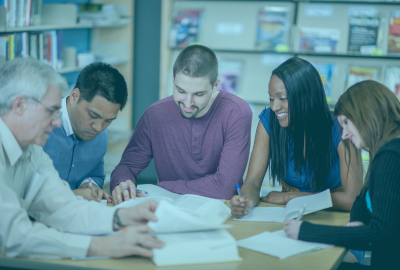 Grupo de estudiantes y docentes colaborando en una biblioteca, representando la formación en la Maestría en Educación en CONAEC.
